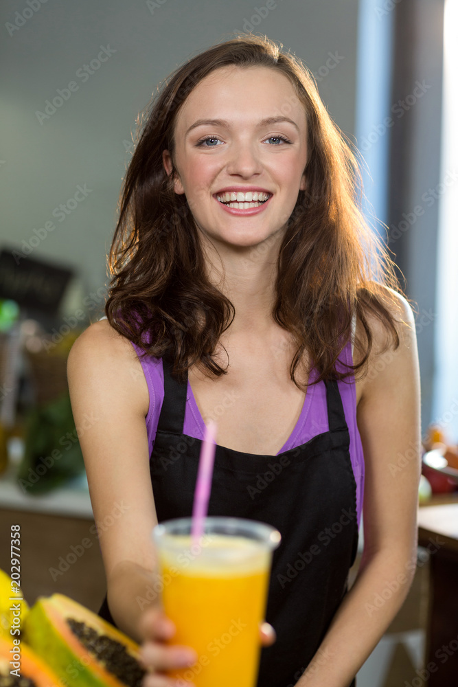 Smiling shop assistant offering the juice at the counter Smiling shop assistant offering the juice at the counter