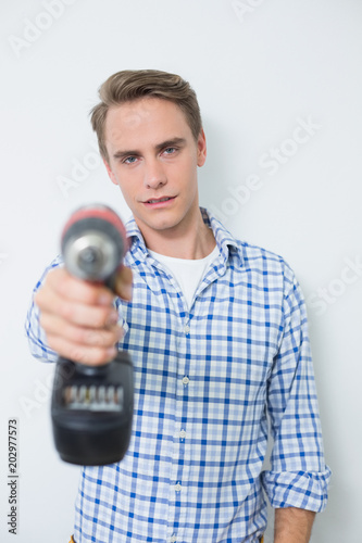 Portrait of a smiling handsome young handyman holding drill