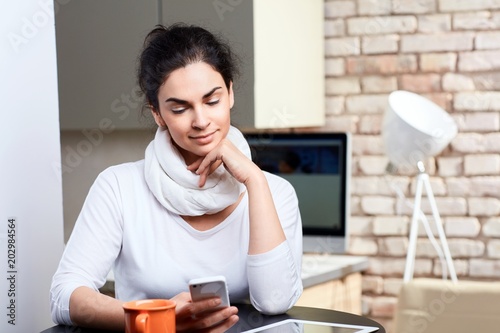 Female blogger writing post on smartphone at home