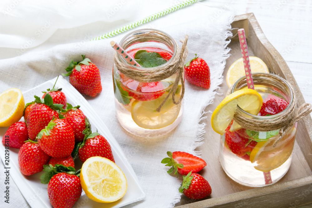Mineral water with fresh strawberries, lemon and mint in jar on a white wooden background, copy space Mineral water with fresh strawberries, lemon and mint in jar on a white wooden background, copy space
