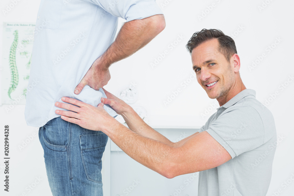 Obraz premium Side view of a male physiotherapist examining mans back