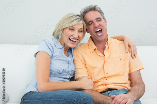 Cheerful couple sitting on sofa at home © WavebreakmediaMicro