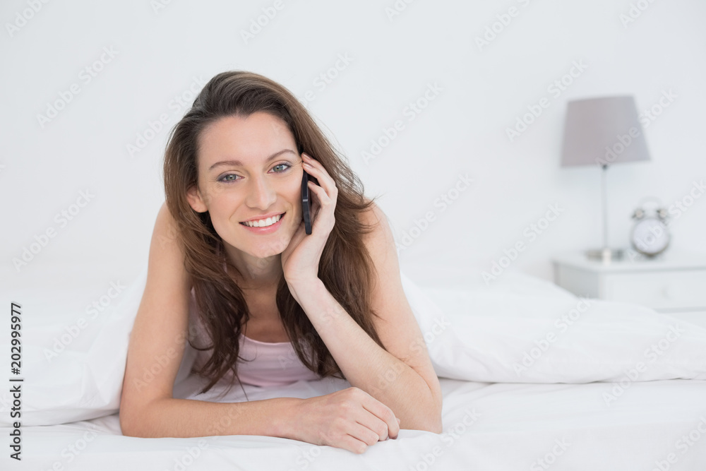 Portrait of a smiling woman using mobile phone in bed Portrait of a smiling woman using mobile phone in bed