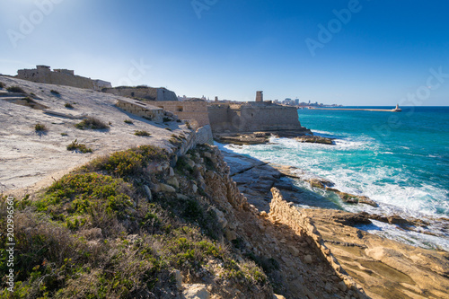 Turquoise waves crash against the ancient limestone fortress seaward walls of Fort Ricasoli, Knights of St John UNESCO fortification, today used as film set, Kalkara, Malta, March 2017