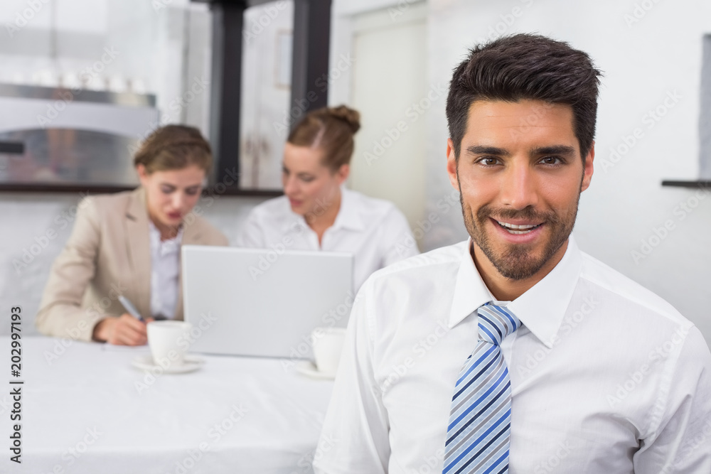 Smiling businessman with colleagues at office desk Smiling businessman with colleagues at office desk