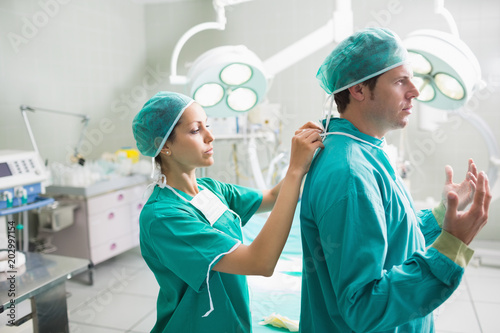 Side view of a nurse helping a surgeon