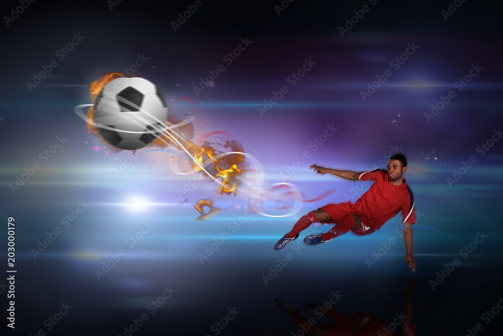 Football player in red kicking against black background with spark