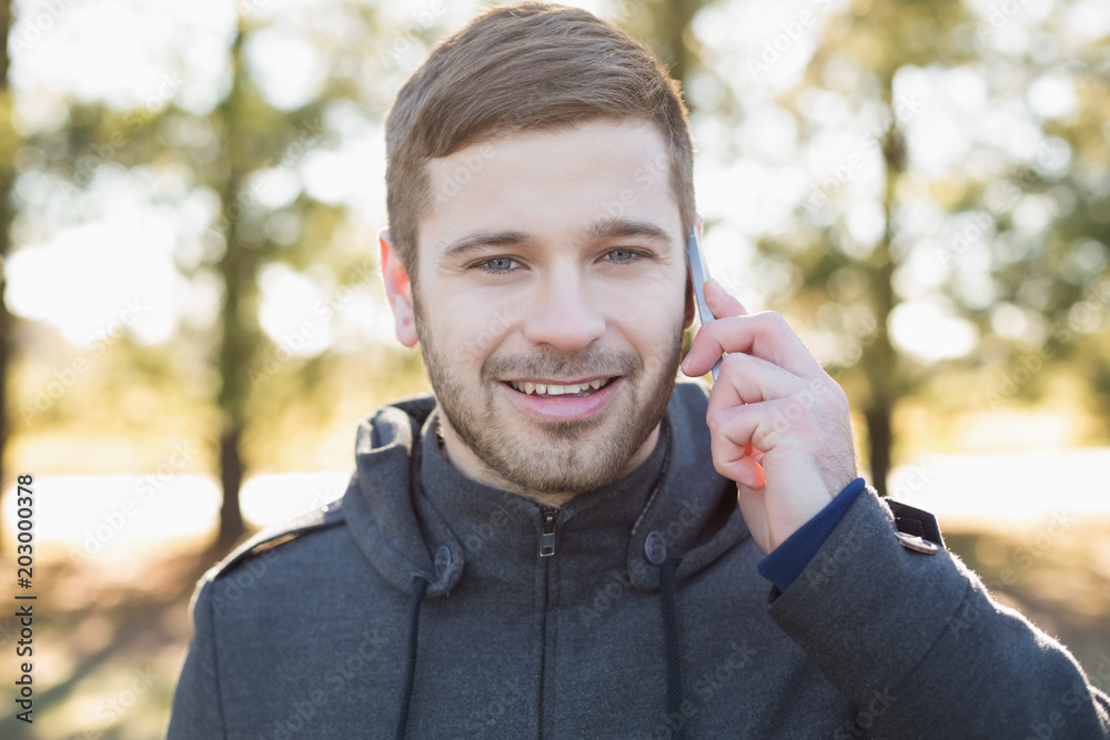 Smiling man using mobile phone in the forest Smiling man using mobile phone in the forest