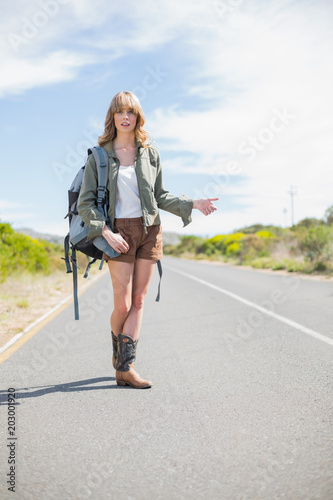 Natural blonde woman posing while hitchhiking