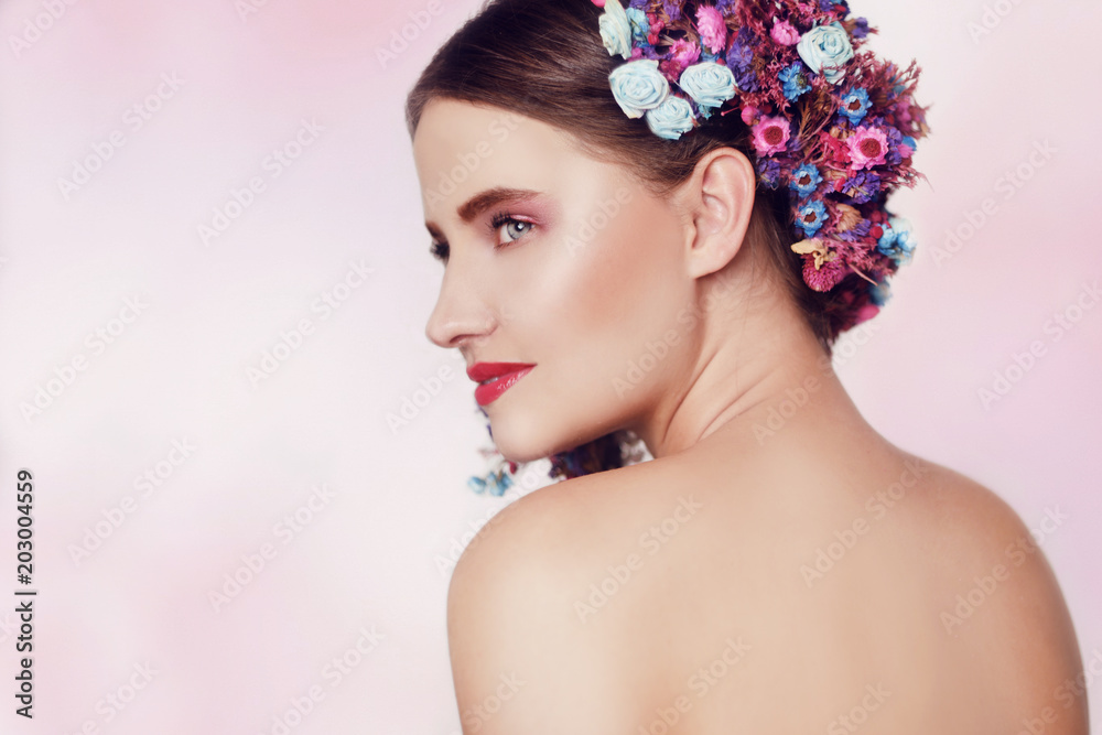 Beautiful young woman with delicate flowers in their hair. Beauty Girl with Flowers Hairstyle.Model portrait with Summer pink and blue Flowers. Hairstyle with flowers. Fantasy portrait in pink. Smile. Beautiful young woman with delicate flowers in their hair. Beauty Girl with Flowers Hairstyle.Model portrait with Summer pink and blue Flowers. Hairstyle with flowers. Fantasy portrait in pink. Smile.