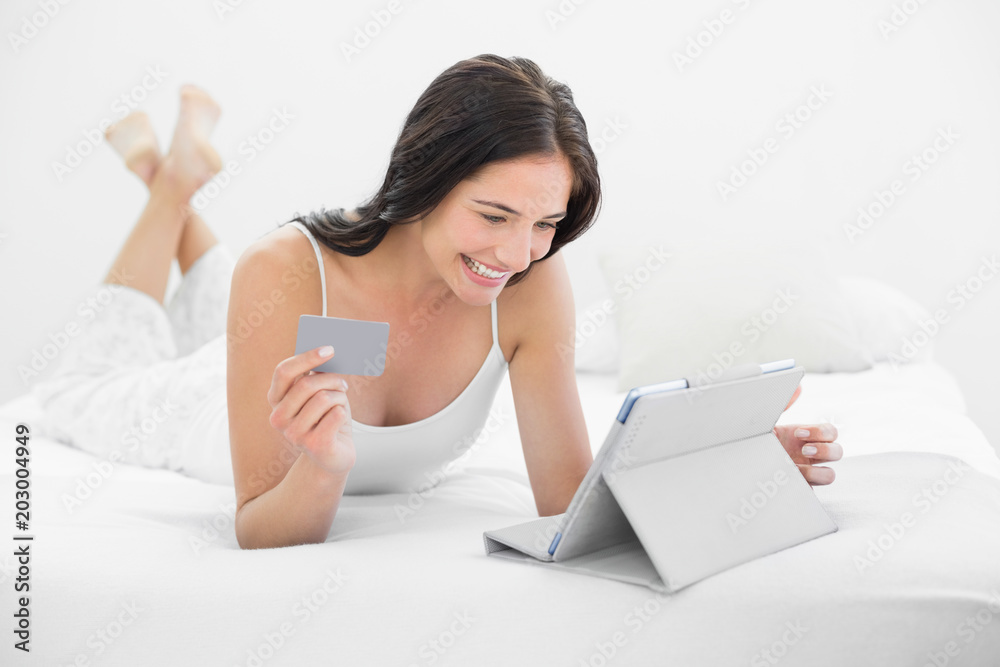 Casual young woman doing online shopping in bed Casual young woman doing online shopping in bed