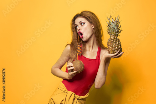 woman with coconut and pineapple makes faces and looks up