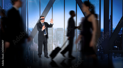 Mature businessman in a blindfold against room with large window looking on city