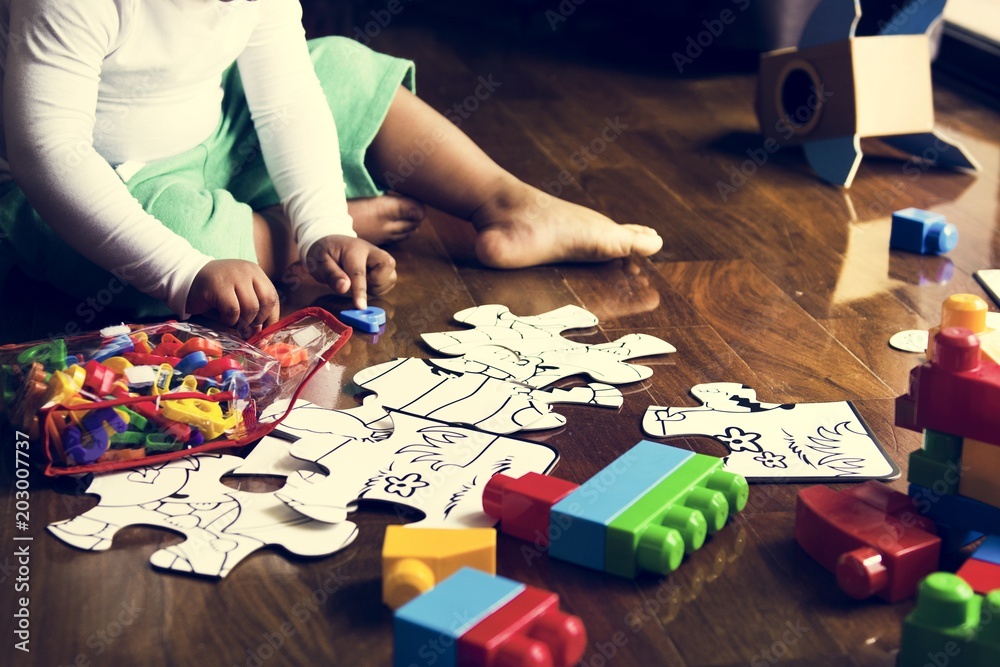 African descent kid enjoying puzzles on wooden floor African descent kid enjoying puzzles on wooden floor