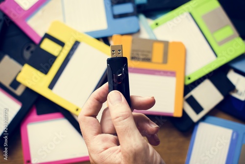 Fototapeta Naklejka Na Ścianę i Meble -  Hand holding USB drive with floppy disk background