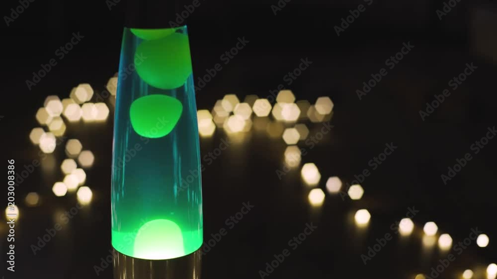 4k lava lamp retro vintage hippie abstract background, green wax moving floating. Bokeh of the garlands in background