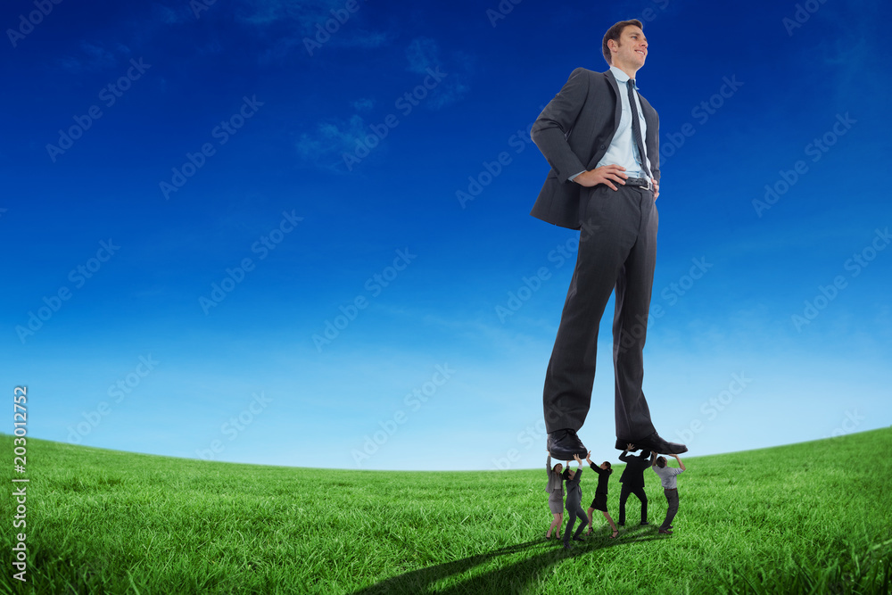 Business people supporting boss against green field under blue sky Business people supporting boss against green field under blue sky