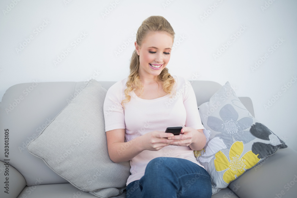 Casual smiling blonde using smartphone