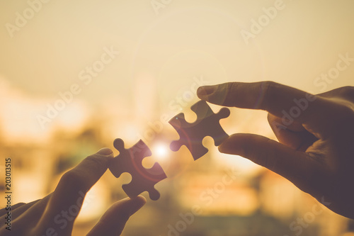 Silhouette Woman hands connecting couple puzzle piece against sunrise effect, businesswoman holding jigsaw with sunset background. Business solutions, target, success, goals and strategy concepts photo