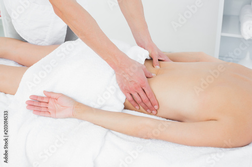 Mid section of a physiotherapist massaging womans back