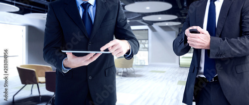 Focused businessman texting on his mobile phone against college