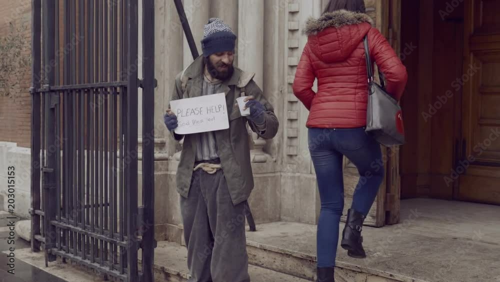 homeless in front of a church receives alms from a woman homeless in front of a church receives alms from a woman