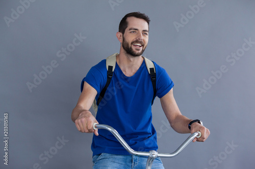 Man in blue t-shirt and back posing sitting on a bicycle