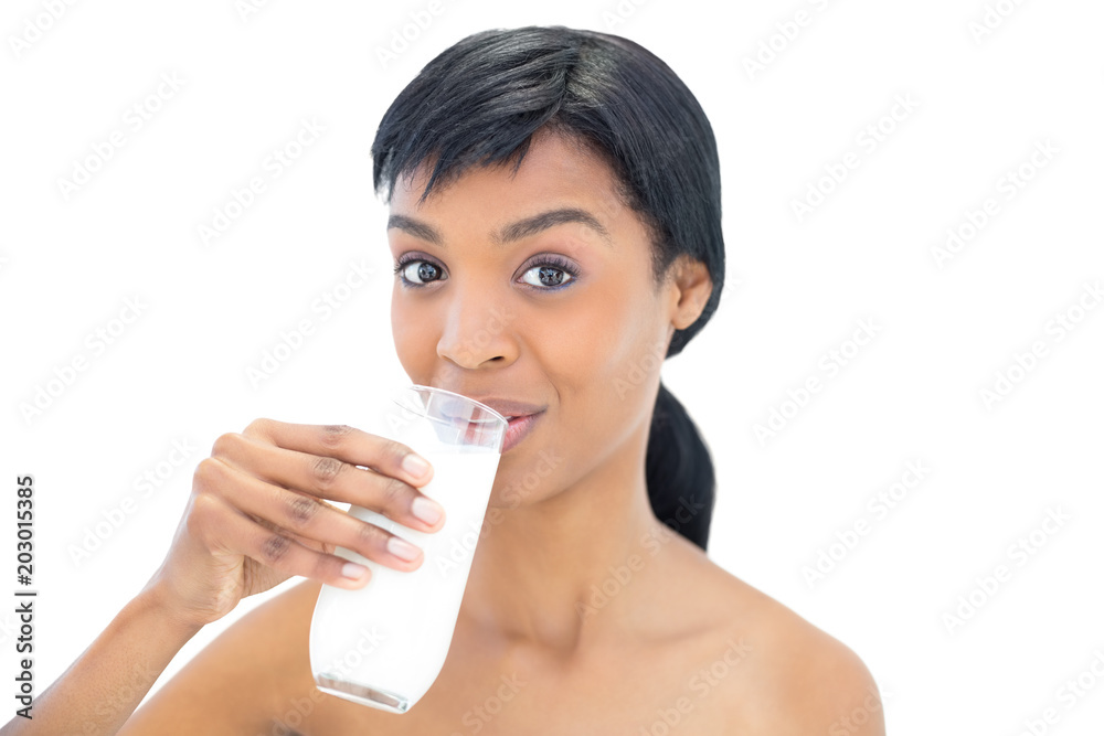 Delighted black haired woman drinking a glass of milk