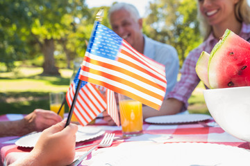 Happy family having picnic and holding american flag