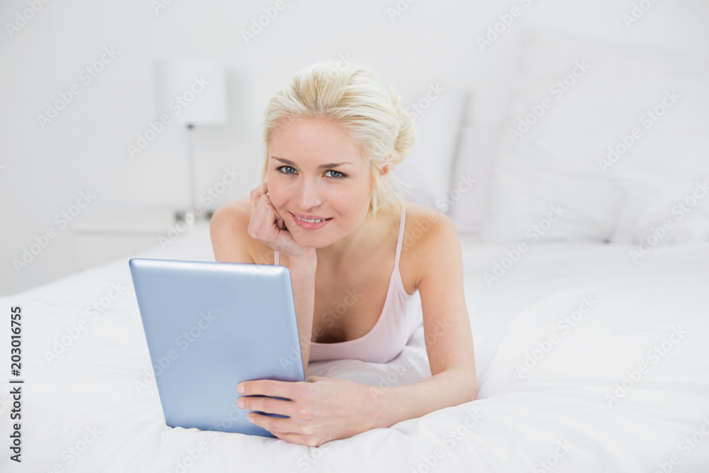 Smiling casual young blond with tablet PC in bed Smiling casual young blond with tablet PC in bed