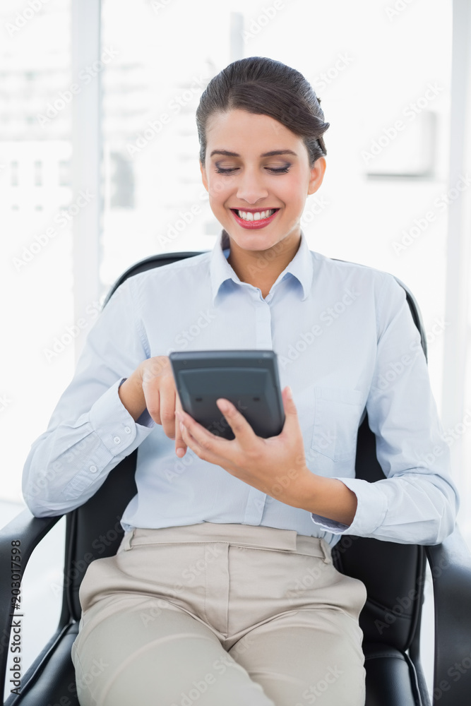 Content classy brown haired businesswoman using a calculator Content classy brown haired businesswoman using a calculator