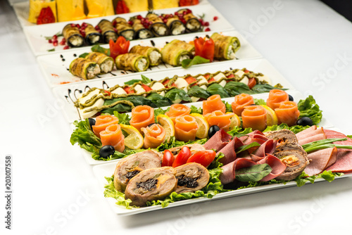 Different snacks for eating on holiday in white plates on white background. Kitchen, menu, food concept . delicious dish