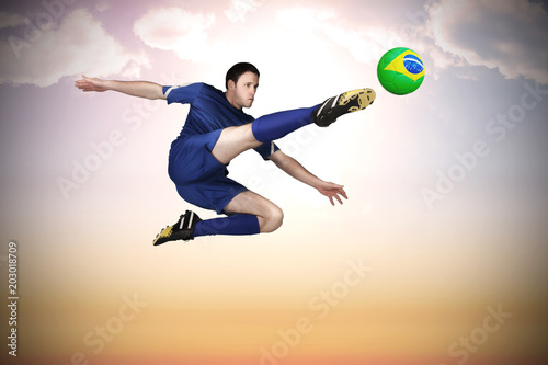Football player in blue kicking against beautiful orange and blue sky © vectorfusionart