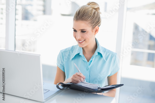 Happy well dressed businesswoman writing on datebook