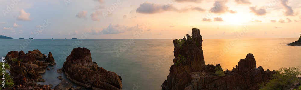 Fototapeta premium Large rocks and spiky filed in sea green waters and golden evening sky. Long Exposure Photography Technique .Chai Chet, Koh Chang, Trat, Thailand