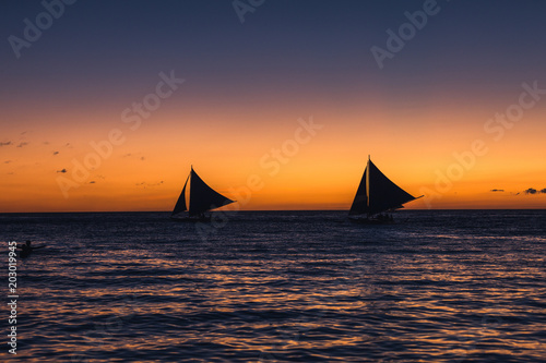 Two outrigger sailboats on the horizon
