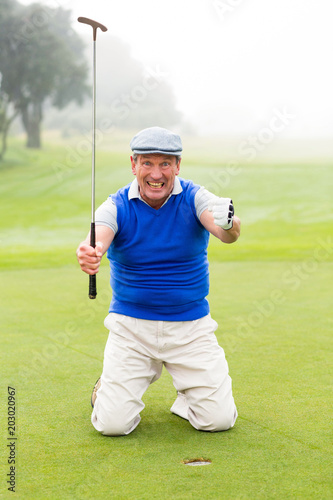 Kneeling golfer cheering on putting green 