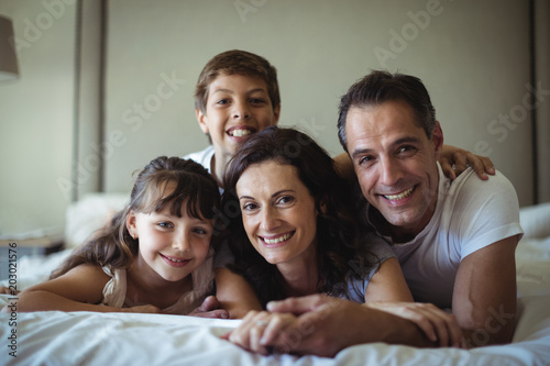 Portrait of happy family lying on bed in bedroom