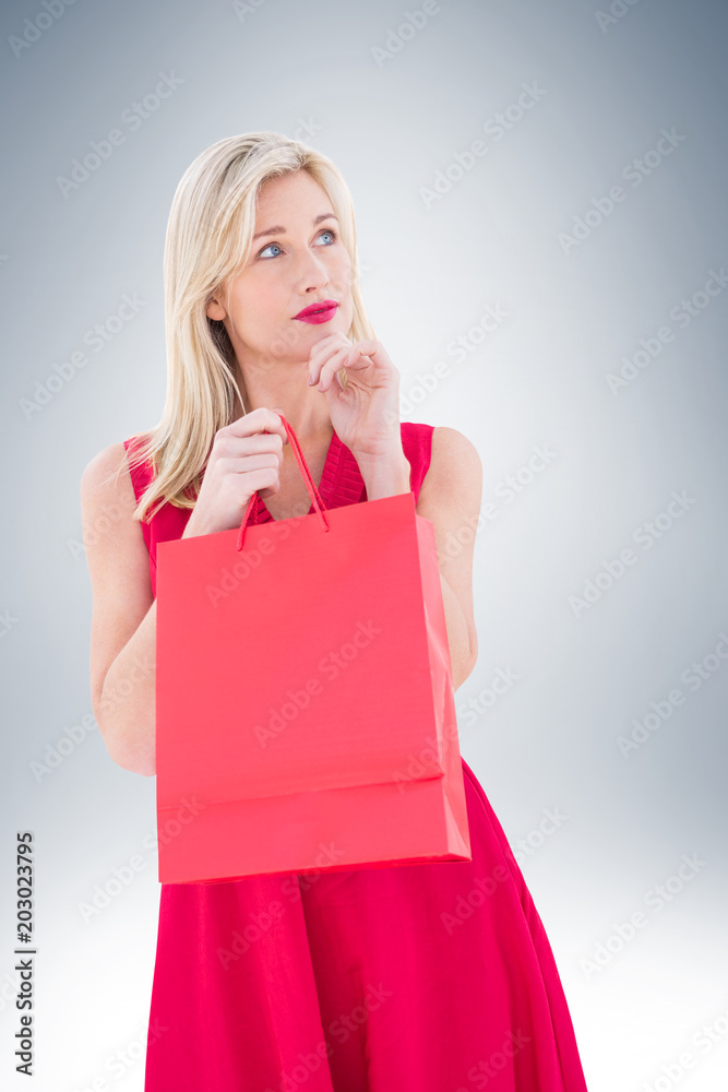 Stylish blonde in red dress opening gift bag on vignette background Stylish blonde in red dress opening gift bag on vignette background