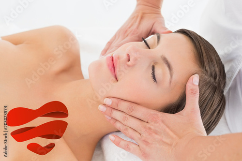 Attractive young woman receiving facial massage at spa center against heart