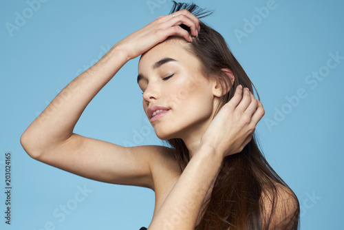 woman straightens her hair on a blue background