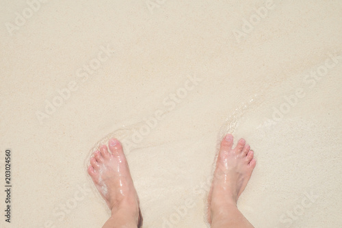 Top view barefoot standing on sand at sea beach at shore in sunny day,Relaxing in summer vacation travel time.copy space for adding text.