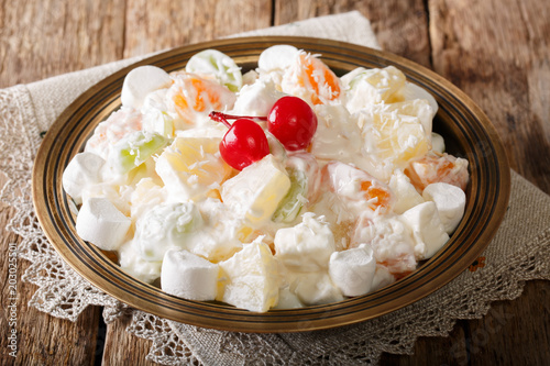 fruit salad from pineapple, oranges, grapes and coconut with marshmallow and vanilla yogurt close-up. horizontal
