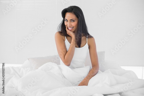 Gorgeous young woman posing sitting on her bed