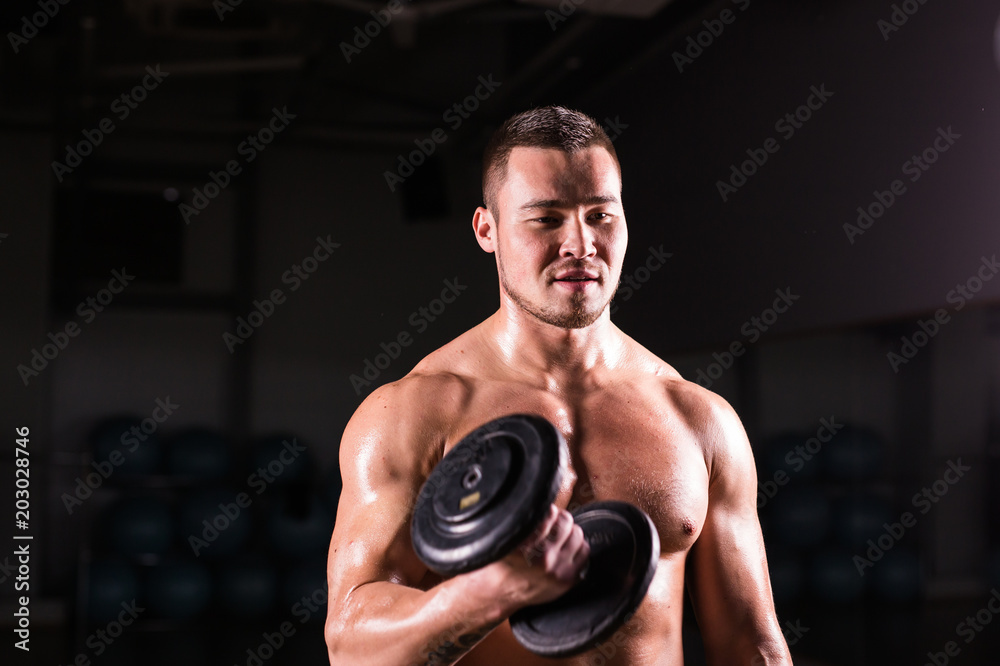 Sporty man doing exercise with dumbbells. Muscular guy on black background. Strength and motivation.