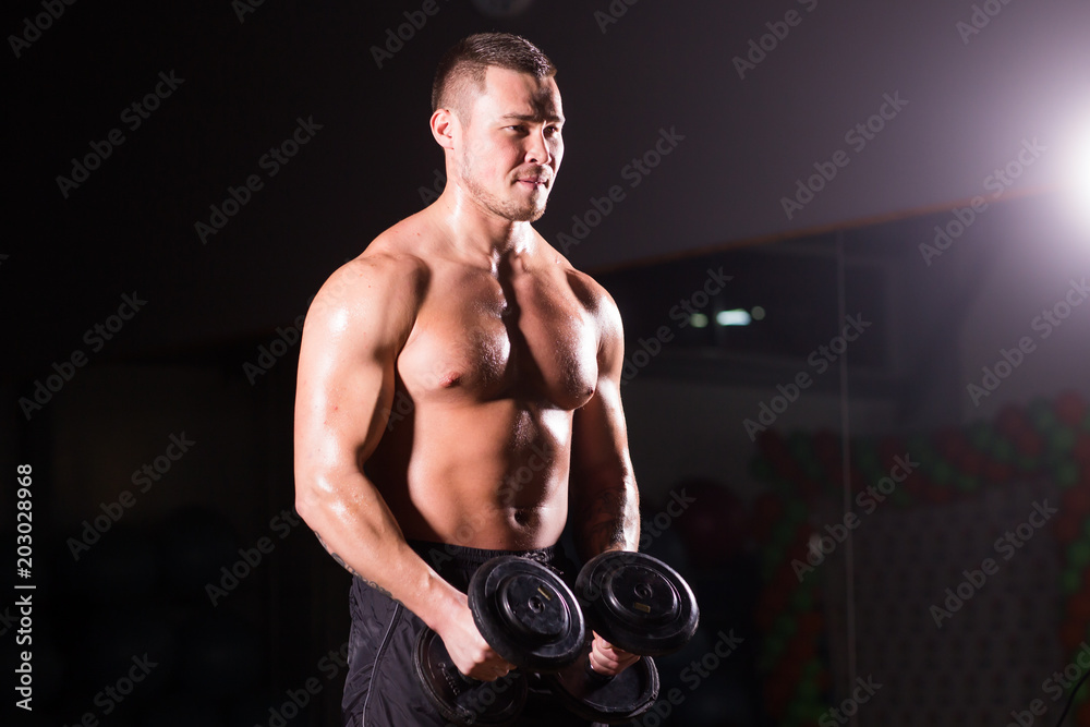 Handsome power athletic man with dumbbell. Strong bodybuilder with six pack, perfect abs, shoulders, biceps, triceps and chest Handsome power athletic man with dumbbell. Strong bodybuilder with six pack, perfect abs, shoulders, biceps, triceps and chest