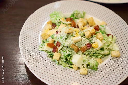 Caesar salad is a green salad of romaine lettuce, Bacon Fried and croutons dressed with lemon juice, olive oil, egg, Worcestershire sauce, garlic, Parmesan cheese, black pepper in white plate 