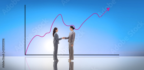 Businesswomen shaking hands against blue sky