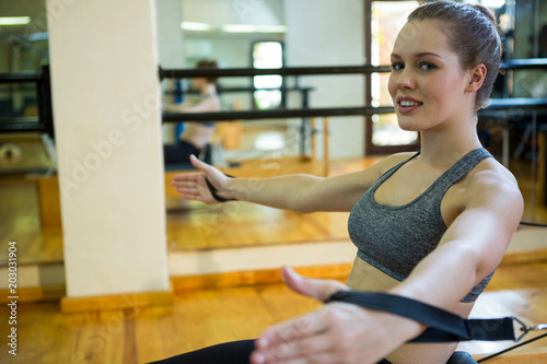 Portrait of beautiful woman practicing stretching exercise on reformer