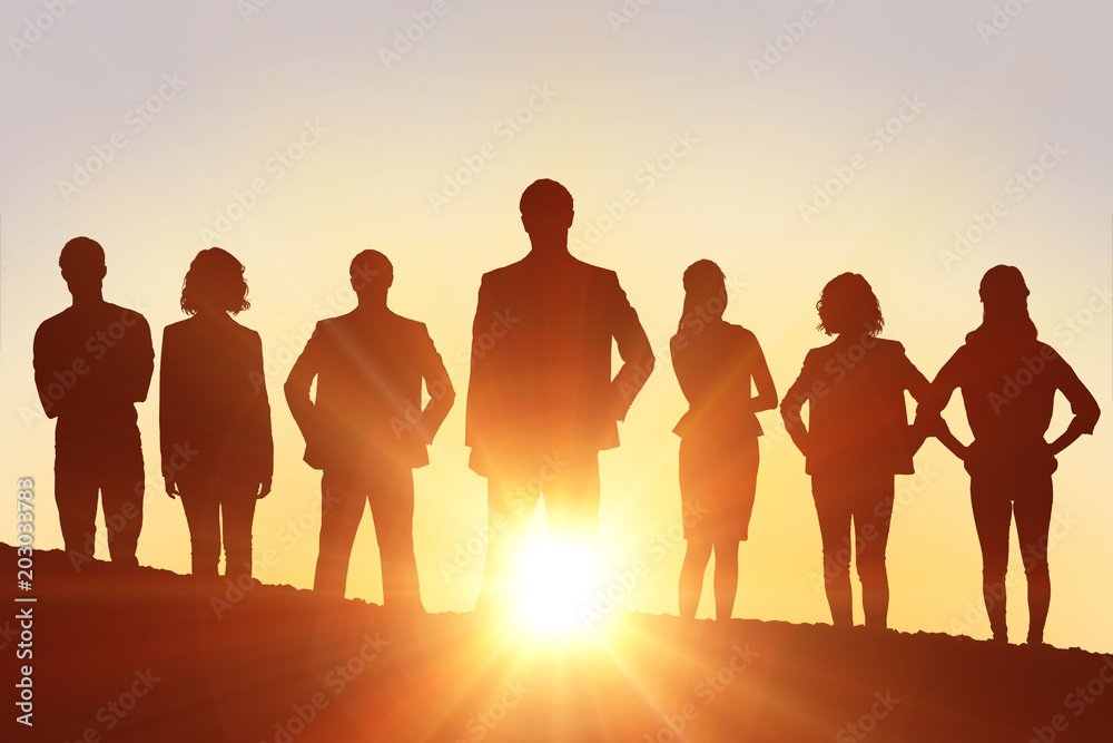 Fototapeta premium Silhouettes standing against a sun set